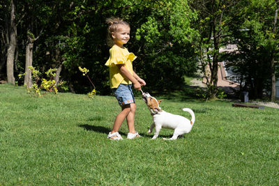 Side view of young woman with dog on grassy field