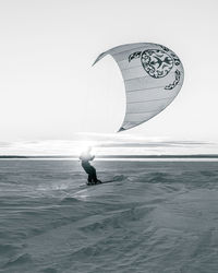 Person with umbrella on sea shore against sky