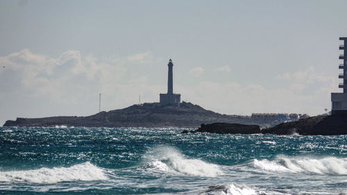 Lighthouse by sea against sky