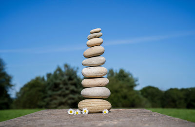 Stack of stones on table against blue sky