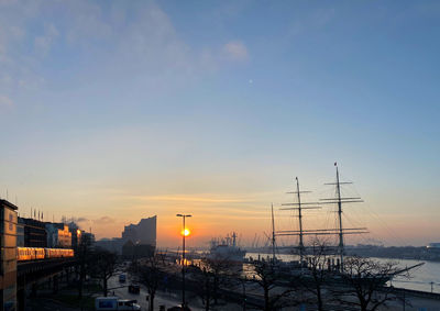 Sailboats in city against sky during sunset