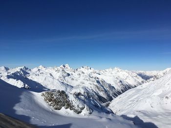 Scenic view of snowcapped mountains against blue sky