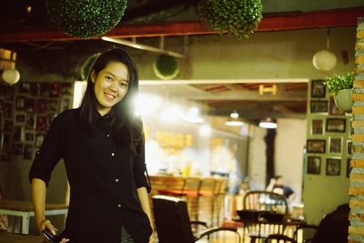 Portrait of a smiling young woman standing in restaurant