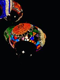 Low angle view of illuminated lighting equipment against black background
