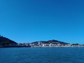 Sea by city against clear blue sky