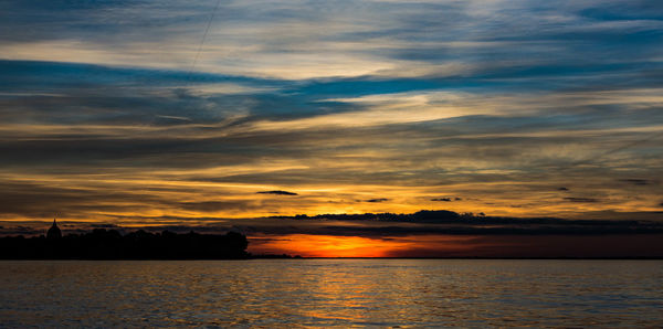 Scenic view of sea against dramatic sky during sunset