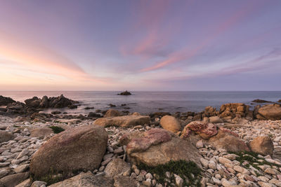 Rocks on beach against sky during sunset