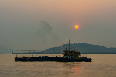 Silhouette ship in sea against sky during sunset