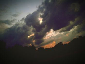 Silhouette of trees against cloudy sky