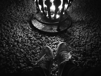 A person warming their feet at an outdoor fire in summer