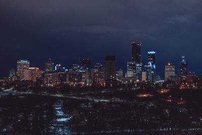 Illuminated buildings in city against sky at night