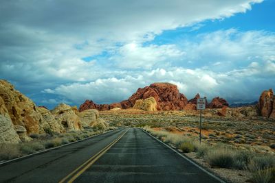 Road leading towards mountains against sky