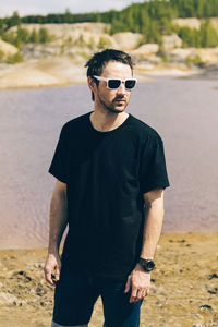 Portrait of young man wearing sunglasses standing on land