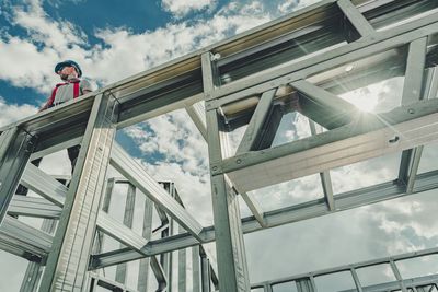 Low angle view of construction worker standing on built structure against sky