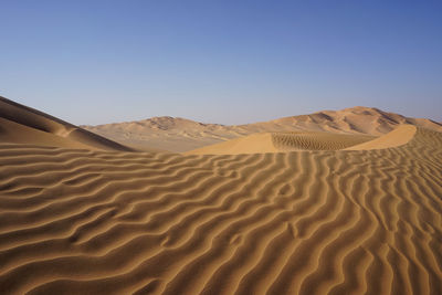Scenic view of sand dunes against clear sky