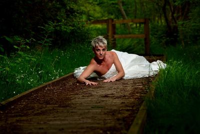 Portrait of bride lying on dirt road in forest