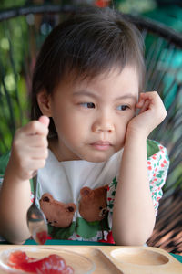 Depressed portrait of 4 years old cute baby asian girl with anorexia. girl bored eating concept.