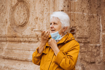 Portrait of young woman standing against wall