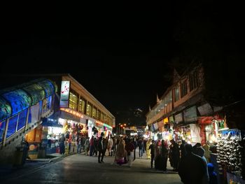 People walking on illuminated street at night