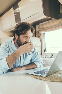 Young woman using laptop while sitting on sofa at home