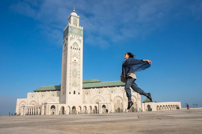 Full length of woman jumping outside hassan ii mosque