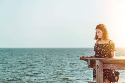 Woman standing by sea against sky