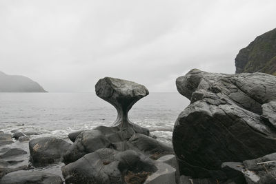 Rock formation on beach against sky