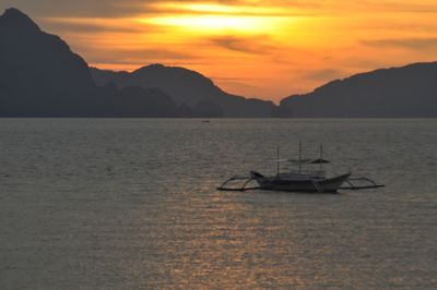 Boats in sea at sunset