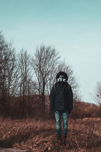 Full length of man with mask standing on bare tree