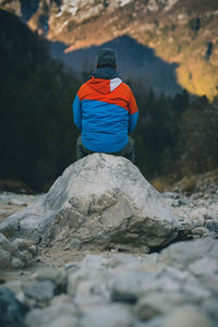 Rear view of man sitting on rock