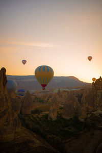 Hot air balloons flying over landscape against sky during sunset