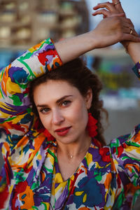 Portrait of young woman with arms raised standing outdoors