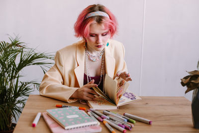 Portrait of young woman using digital tablet while sitting on table