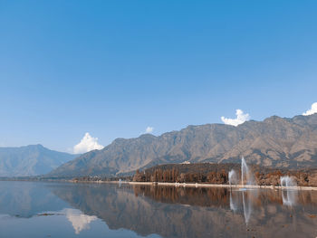 Scenic view of lake and mountains against clear blue sky