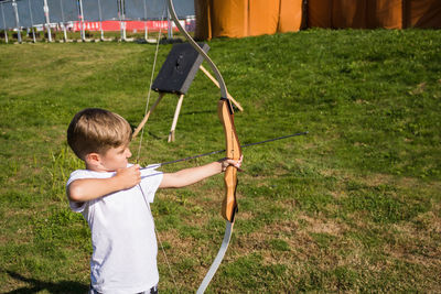 Boy aiming bow while standing outdoor