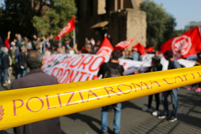 Close-up of text on cordon tape against protestors on road