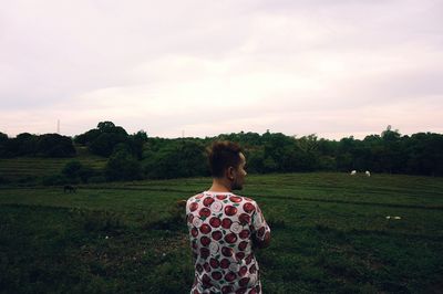 Rear view of woman standing on field against sky