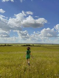 Rear view of woman standing on field against sky