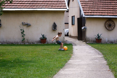 A boy playing soccer in his yard in his swimsui