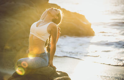 Woman sitting at beach during sunset