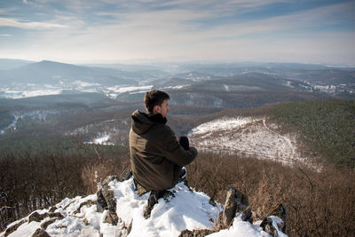 Man sitting on mountain looking at view