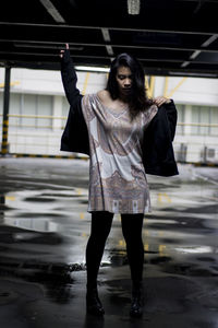 Full length of young woman standing on wet floor in parking lot