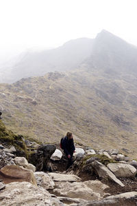 People sitting on rock by mountains against sky