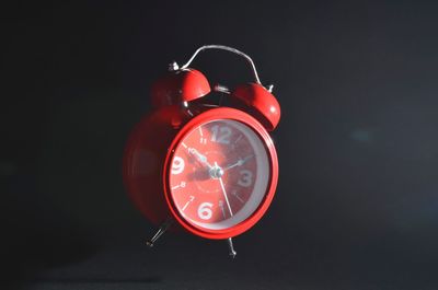 Close-up of red clock against black background