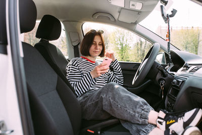 Portrait of young woman using mobile phone while sitting in car