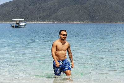Portrait of shirtless man standing in sea