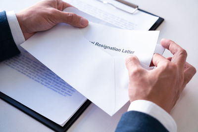 Midsection of man holding paper with text