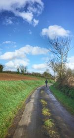 Road amidst field against sky