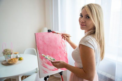 Portrait of young woman using digital tablet while sitting at home