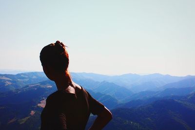 Woman looking at mountains against clear sky